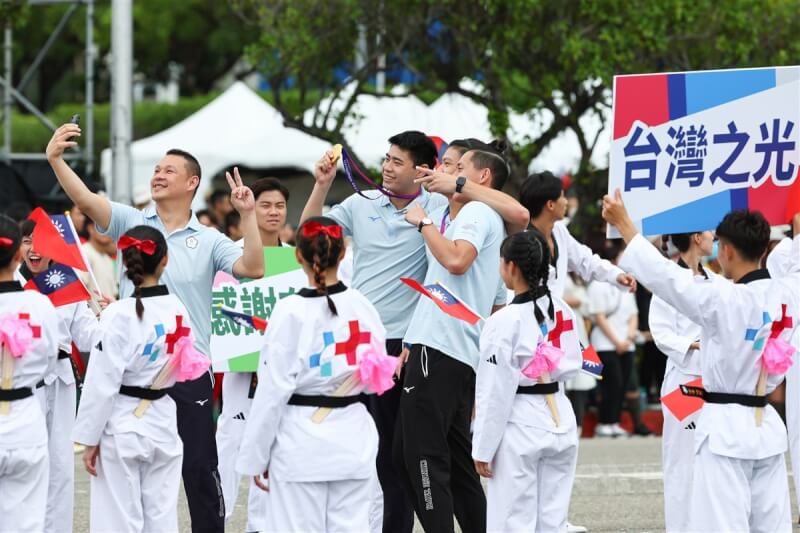 在杭州亞運男子3對3籃球大放異彩、幫助台灣拿下史無前例籃球金牌的選手林信寬(中)等進場,拿著金牌與隊友合影,也接受現場民眾的喝采及表揚。中央社記者王騰毅攝 112年10月10日