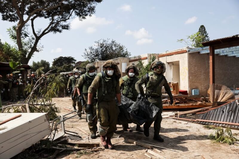 以色列士兵10日在以色列卡法阿扎抬著遭哈瑪斯武裝分子襲擊的受害者遺體。（路透社）