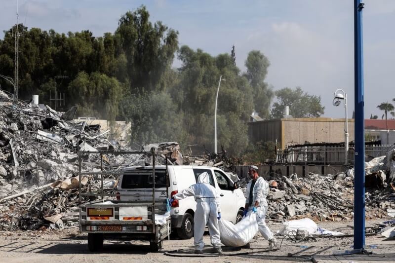 圖為11日，以色列南部史德洛特救援人員在被摧毀的警察局附近清除屍體。（路透社）
