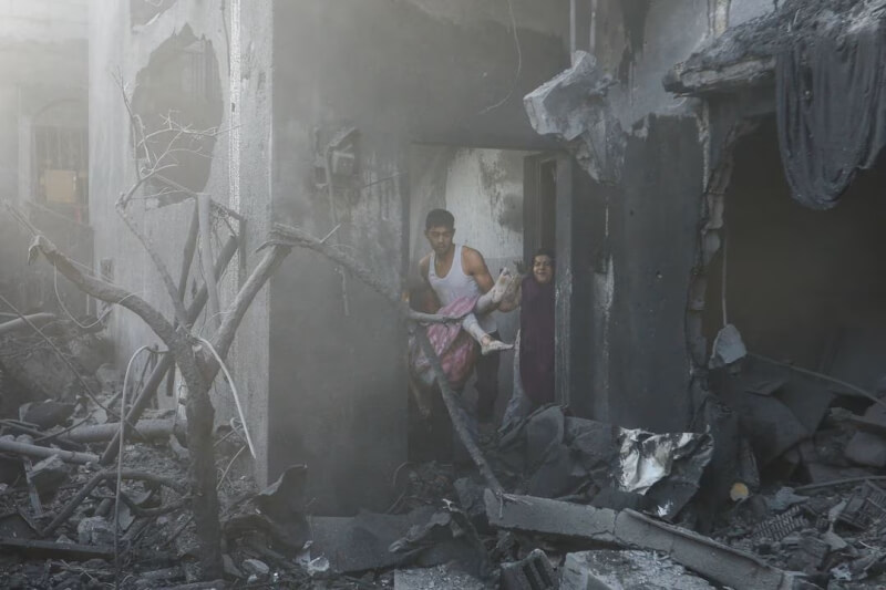 圖為11日加薩一處遭襲擊的房屋，一名男子抱著受傷的巴勒斯坦女孩。（路透社）
