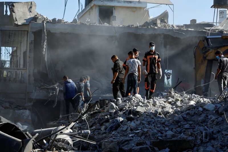 以色列對加薩走廊發動攻擊後，摧毀大量建物，巴勒斯坦人13日行走於在廢墟中。（路透社）