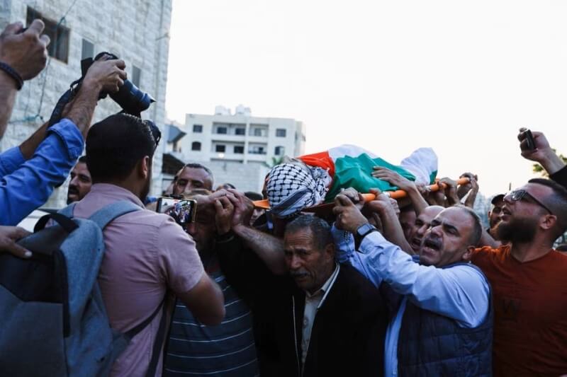 圖為11日約旦河西岸那不魯斯哀悼者抬著1名巴勒斯坦人的遺體。（路透社）