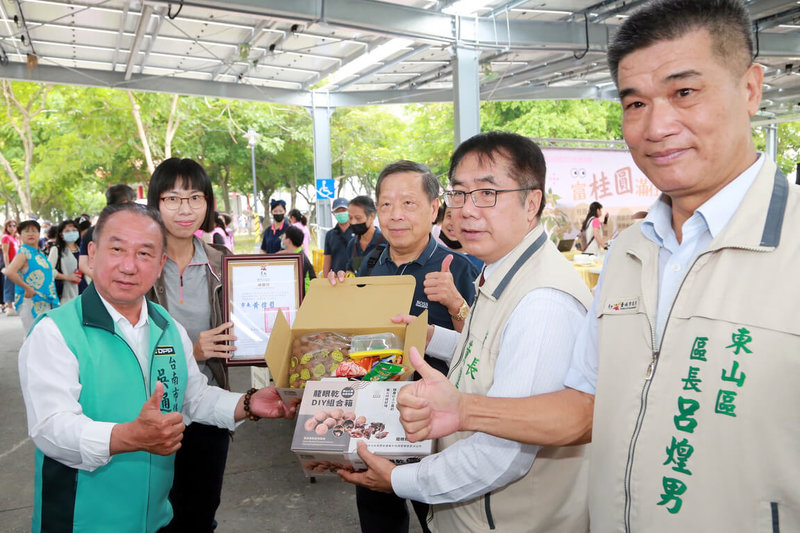 台南市長黃偉哲（右2）15日上午出席在東山區運動公園舉辦的桂圓節開幕活動，參觀現場各攤位，並協助推廣龍眼或桂圓等製成的相關副產品。（台南市政府提供）中央社記者楊思瑞台南傳真  112年10月15日