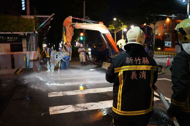 新竹縣竹北市光明六路與縣政七街路口15日傍晚發生自來水及瓦斯外洩，初步了解為建案工地施工造成，目前大型機具已於晚間進場將路面刨開修復管線。圖為工程人員持續搶修，消防人員在旁待命警戒。（新竹縣政府提供）中央社記者魯鋼駿傳真  112年10月15日