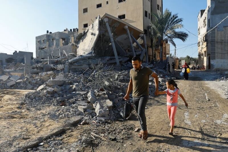加薩走廊南部居民，走過被以色列炸毀的房屋廢墟。（路透社）