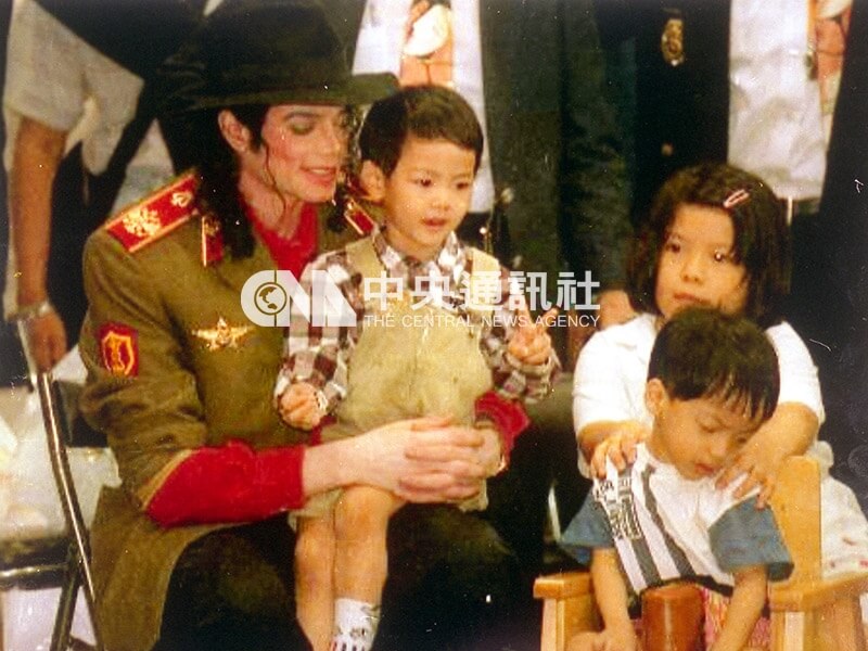 麥可傑克森親切地抱起3歲小朋友坐在他腿上。（中央社檔案照片）