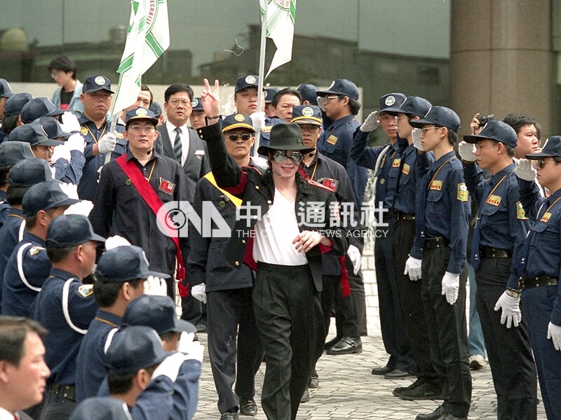 1996年10月23日美國搖滾歌星麥可傑克森離開下榻的晶華酒店時，受到大批保全人員列隊行舉手禮歡送。麥可面帶微笑向歌迷揮別。（中央社檔案照片）