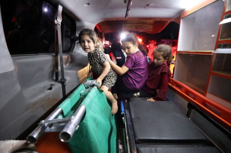 加薩市阿里阿拉伯醫院17日遭空襲後，孩童被送上救護車。（路透社）