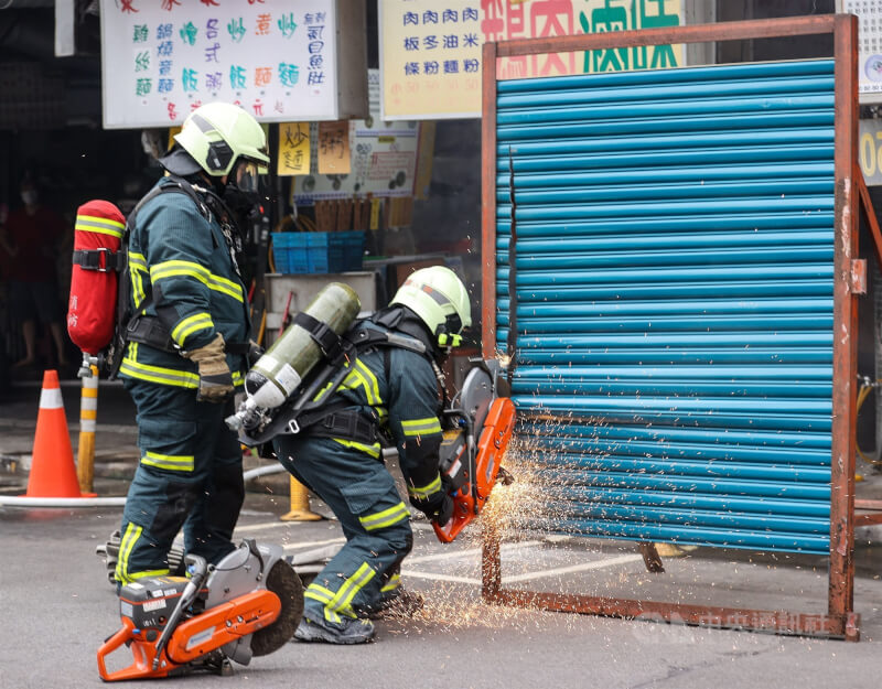 圖為台北市消防員執行搶救演練，模擬大樓意外發生火警，以機具破門搶救。（中央社檔案照片）