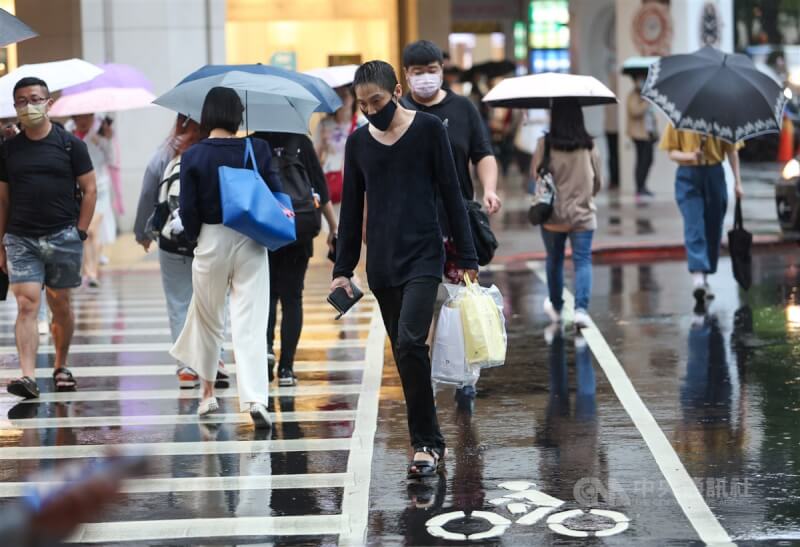 中央氣象署表示，27日起至30日受東北季風及華南雲雨區影響，各地降溫，易有短暫雨。圖為台北市南西商圈部分逛街民眾撐傘過馬路。（中央社檔案照片）