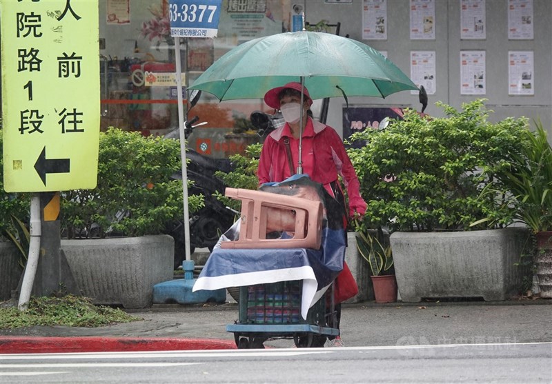 圖為22日北市南港區民眾撐傘推車。（中央社檔案照片）