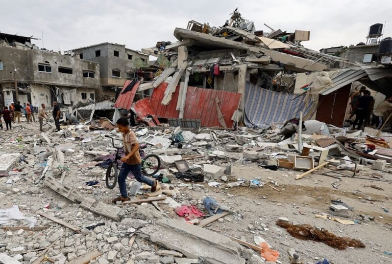 圖為加薩走廊南部遭以色列空襲，一名兒童27日走在建物殘骸上。（路透社）