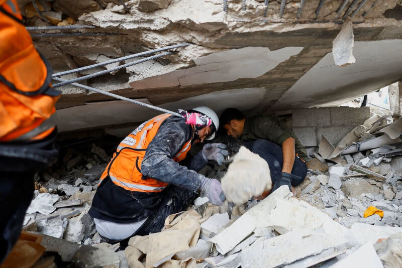 加薩走廊南部甘尤尼斯地區搜救人員29日在倒塌的房屋中尋找傷亡者。（路透社）