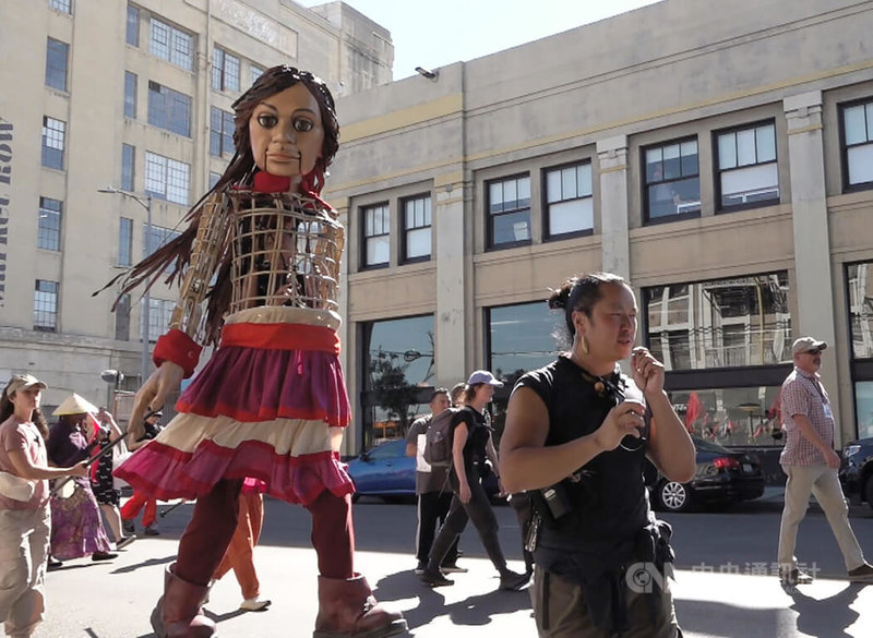 大型木偶行動劇小艾瑪爾（Little Amal）2日在洛杉磯街頭演出，偶戲導演魏道揚（Enrico Dau Yang Wey）身上帶著通訊裝置，臨場指導操偶師。中央社記者林宏翰洛杉磯攝 112年11月3日