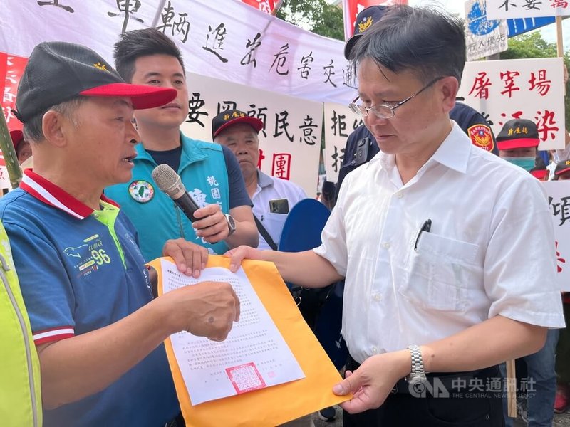 近300名桃園新屋笨港里民9日抬媽祖神像赴農業部抗議,訴求不要電宰場;並由笨港里長黃建興(左)遞交陳情書給農業部畜牧司長張經緯(右)。中央社記者楊淑閔攝 112年11月9日