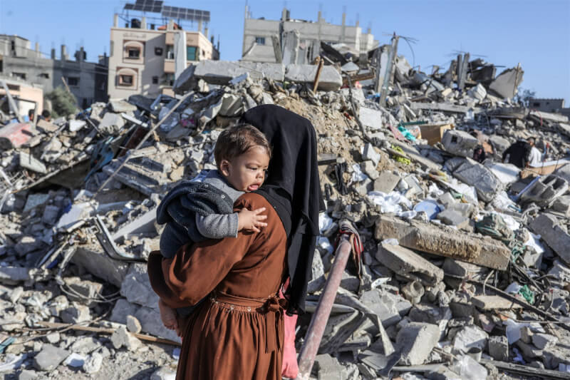 10日加薩走廊被以色列空襲後，建築物毀損，一名婦人抱著孩子。（安納杜魯新聞社）