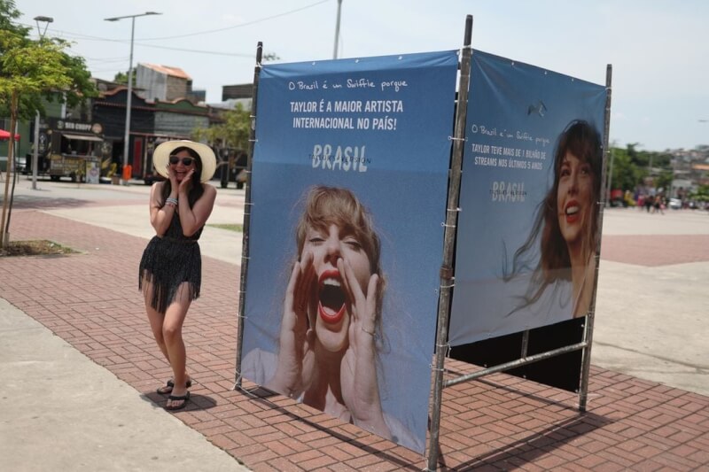 18日巴西里約熱內盧一名泰勒絲的粉絲在演唱會前，與宣傳看板合影。（路透社）