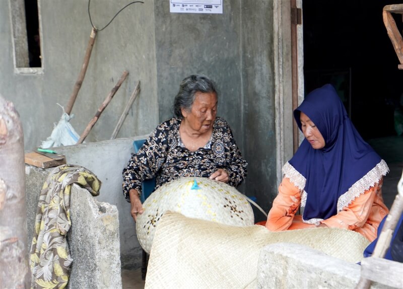 中資赴印尼巴淡設廠，造成島民必須抗爭求生存。年邁的老婦人阿姆拉（Amlah）（左）與女兒莎曼（Saamah）（右）一起編織竹帽，她們不願搬離住了一輩子的祖厝。中央社記者李宗憲林邦島攝 112年11月22日