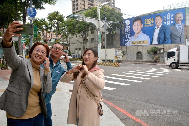國民黨新北市立委參選人葉元之先前在板橋區一處路口高掛他與國民黨總統參選人侯友宜、民眾黨總統參選人柯文哲的競選廣告,但藍白合如今確定破局,這幅廣告何去何從也引發關注,民進黨新北市議員黃淑君(左)24日特地與團隊成員到場自拍記錄。中央社記者黃旭昇新北市攝 112年11月24日