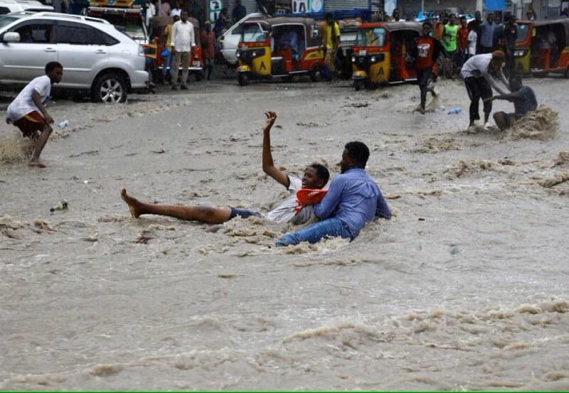 索馬利亞正面臨滂沱大雨襲擊，9日摩加迪休街上一名男子試圖從洪水中救出一名男孩。（路透社）