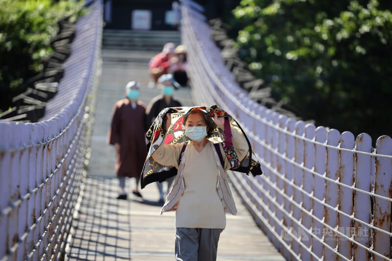 圖為民眾近午時到台北白石湖吊橋，用外套遮擋太陽。（中央社檔案照片）