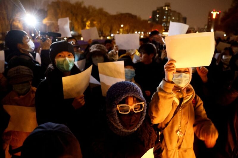 圖為去年11月27日，中國民眾在北京街頭手舉白紙抗議防疫政策。（路透社）