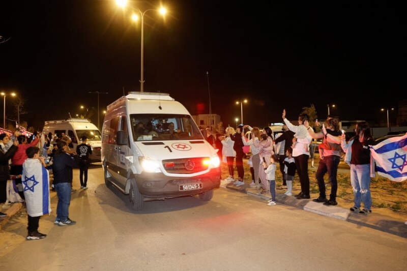 圖為26日以色列歐發金，民眾夾道迎接載有獲釋人質的車隊。（路透社）