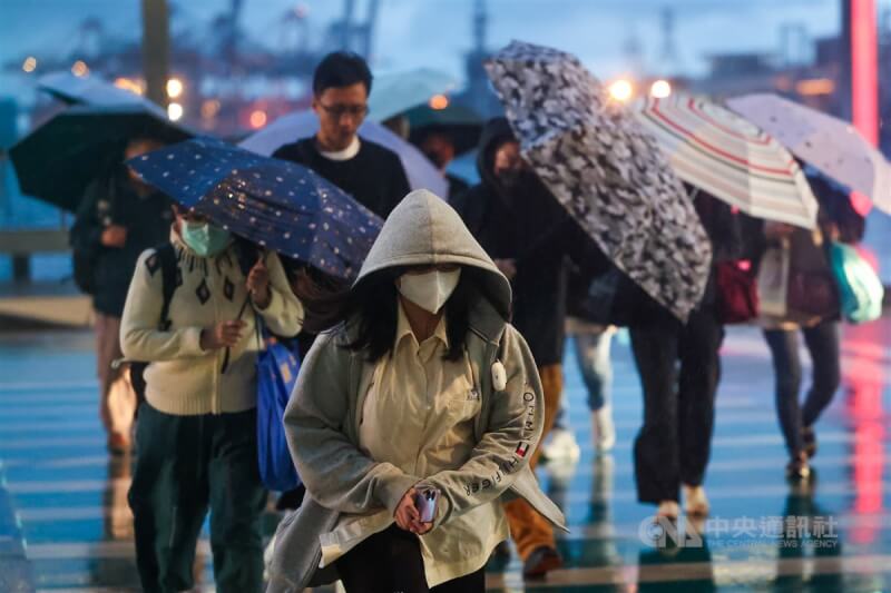 圖為基隆港周邊行人撐傘、戴帽遮擋雨勢。（中央社檔案照片）