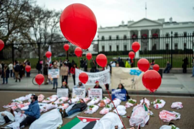 挺巴勒斯坦的示威者2日聚集美國白宮外，多人蓋白布躺地示威。（路透社）