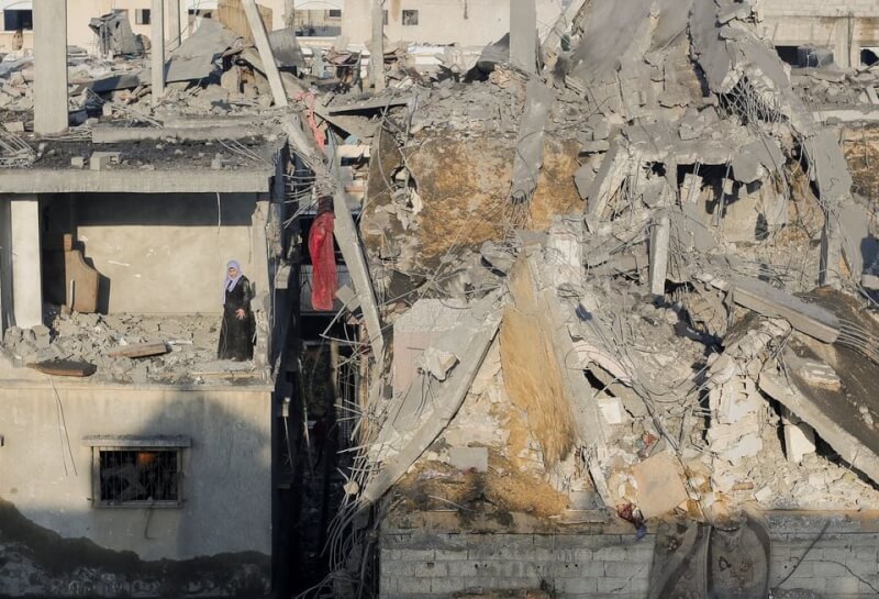 圖為一名巴勒斯坦婦女站在加薩南部甘尤尼斯一棟被擊毀的建築物中，察看被以色列轟炸的地方。（路透社）