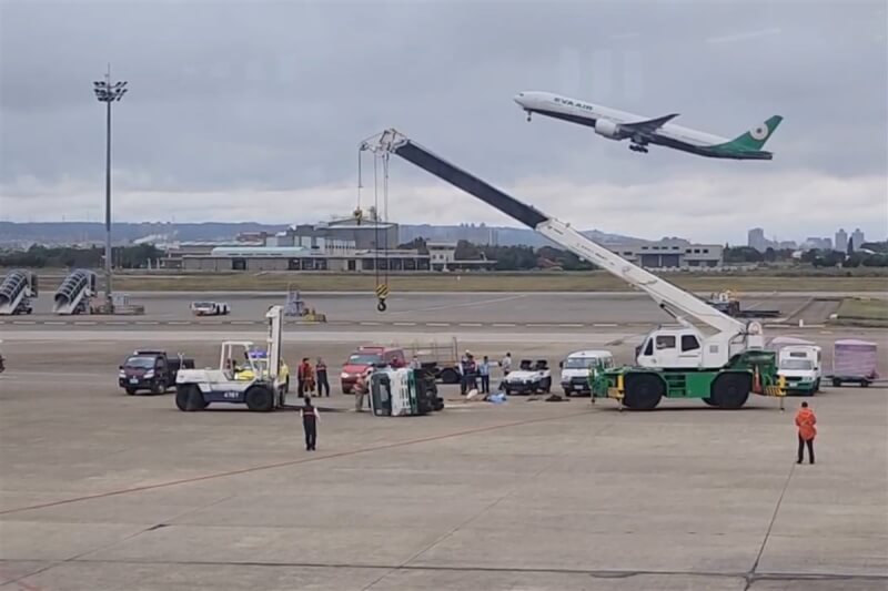 航空警察局12日表示，桃園航勤員工駕駛拖車頭與長榮航太員工駕駛的航機電源車在機坪發生碰撞，導致航機電源車往右翻覆在地，工作人員請來吊車到場協助。（讀者提供）中央社記者吳睿騏桃園機場傳真 112年12月12日