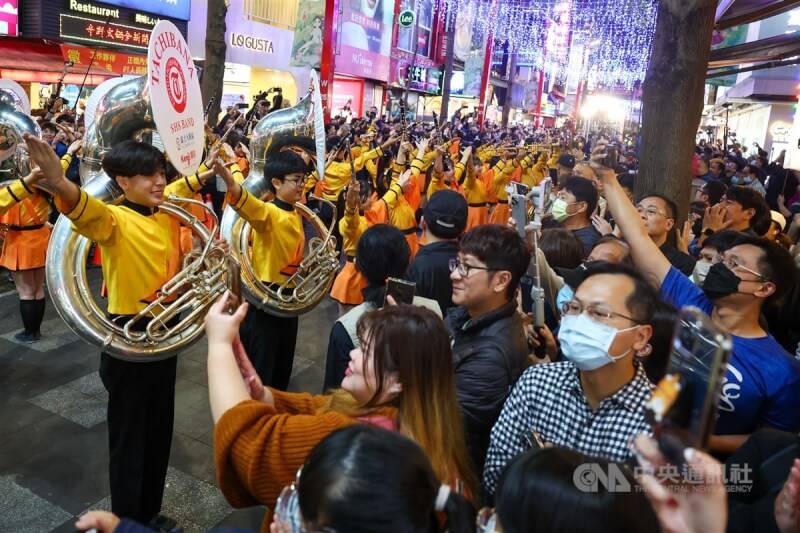 「橘色惡魔」日本京都橘高校吹奏樂部近日應邀再度訪台,12日快閃現身台北西門町商圈踩街演出,街道兩旁擠滿圍觀人潮。中央社記者王騰毅攝 112年12月12日