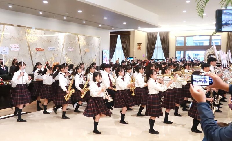 日本京都橘高校吹奏樂部2度訪台掀起「橘色旋風」，12日上午在入住的富士大飯店快閃演出10分鐘，吸引民眾搶拍。（富士大飯店提供）中央社記者王寶兒傳真 112年12月12日