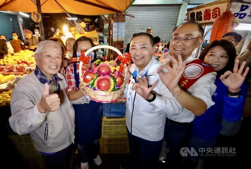 國民黨總統參選人侯友宜（前右3）13日晚間現身高雄市三民區，在同黨立委參選人黃柏霖（前右2）等人陪同下，前往吉林街夜市拜票，現場攤商致贈水果籃預祝當選。中央社記者董俊志攝  112年12月13日