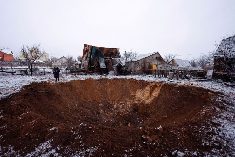 圖為烏克蘭基輔民眾11日站在被俄羅斯飛彈攻擊的坑洞旁。（路透社）