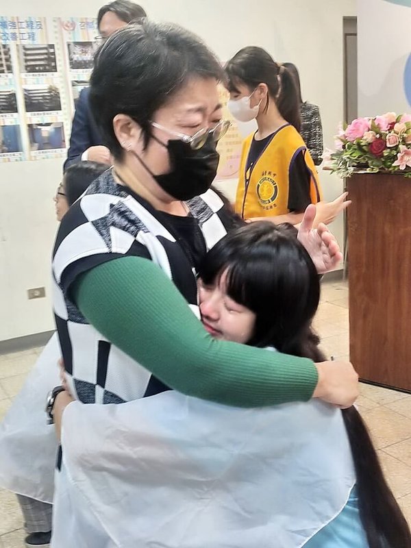 新北市新莊區福營國中15日舉辦「捐髮傳愛」活動,從未剪過短髮的學生林采婕(前右)由母親協助剪下長髮,母女兩人感動相擁落淚。(福營國中提供)中央社記者黃旭昇新北市傳真 112年12月15日