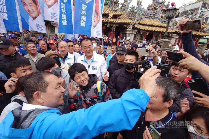 國民黨總統候選人侯友宜（前左）17日前往雲林縣北港朝天宮參拜，受到現場香客熱情歡迎，侯友宜也與民眾一同自拍。中央社記者蔡智明攝 112年12月17日