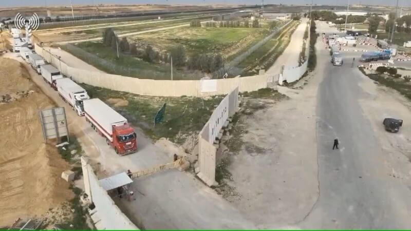 救援物資車隊12日排隊通過以色列和加薩走廊間的克瑞沙洛過境關卡。（COGAT via X/Handout 路透社）