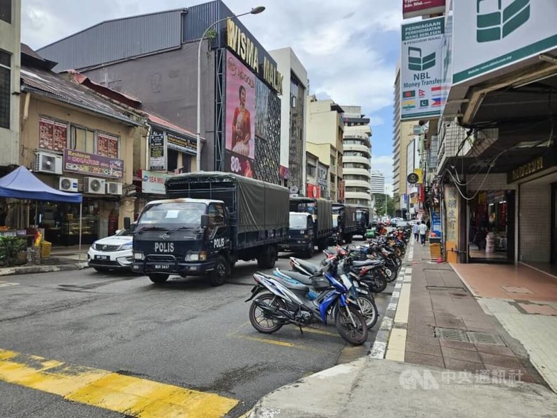 馬來西亞警方21日出動荷槍實彈警力在吉隆坡富都路周邊逮捕非法移工，大批移工四處逃竄。圖為街道上部署的警方車輛與人員。中央社記者黃自強吉隆坡攝  112年12月21日