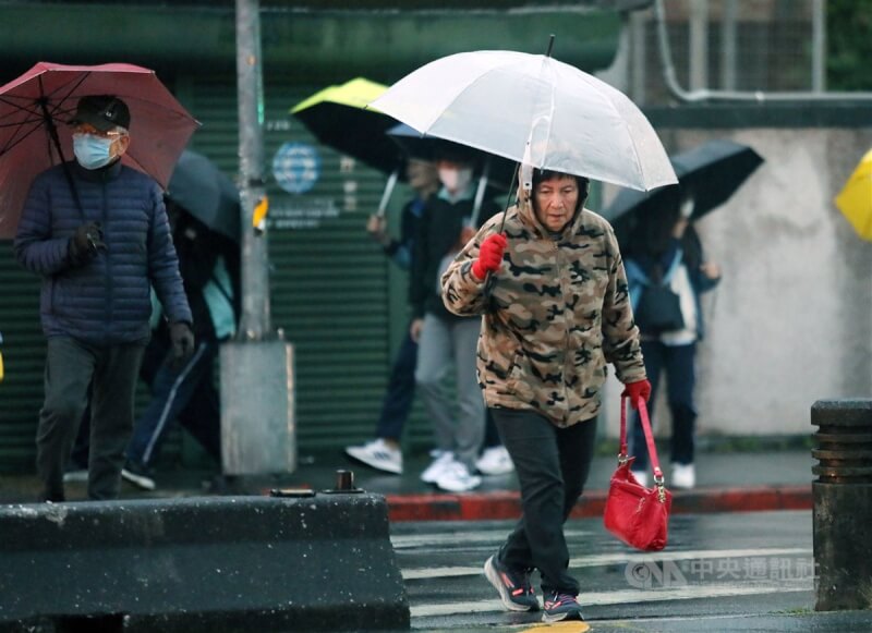 圖為台北市區民眾傍晚撐傘擋雨，戴著保暖手套並拉起帽子加強防寒。中央社記者郭日曉攝 112年12月21日