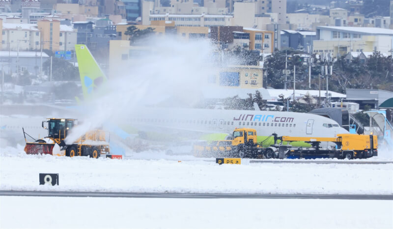 圖為韓國濟州國際機場，一輛鏟雪車正鏟除跑道上的積雪。（韓聯社）