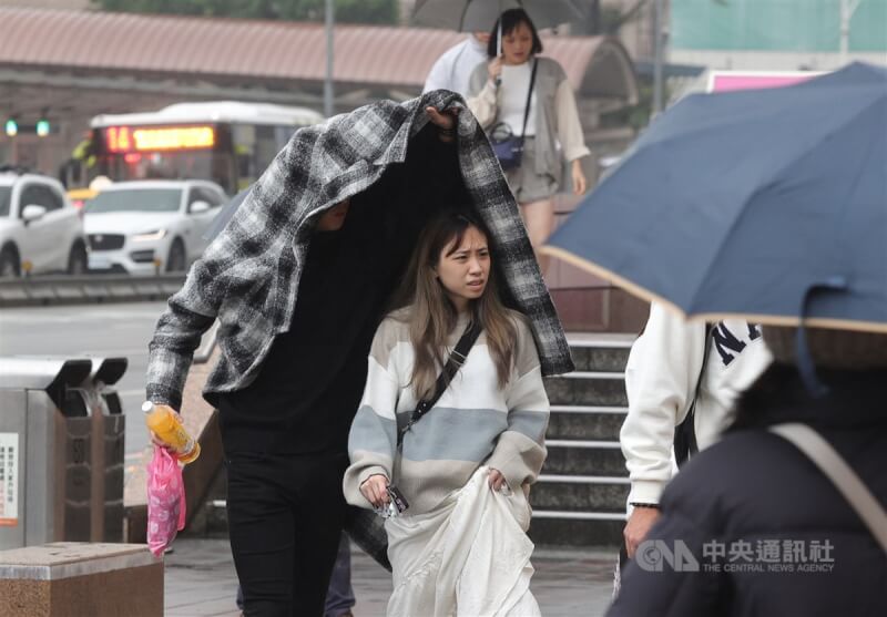 圖為台北市中正區街頭有民眾撐高衣服為同行女生遮擋雨勢。（中央社檔案照片）