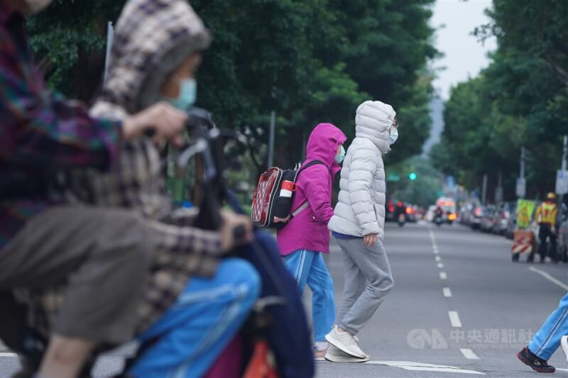 圖為25日民眾在北市北投區送孩子上學，穿外套、戴帽子禦寒。（中央社檔案照片）