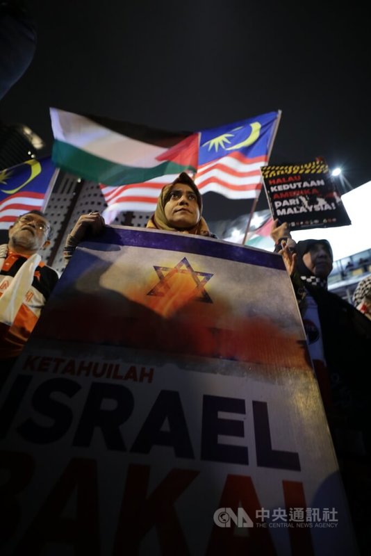 馬來西亞民間社團與政黨共100多人26日晚間遊行到美國大使館附近，手持橫幅抗議布條與看板，表達訴求。中央社記者黃自強吉隆坡攝  112年12月27日