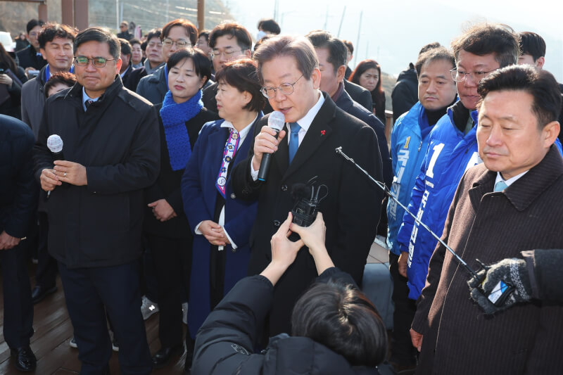 李在明（前排左4）2日上午在釜山視察加德島新機場選址後接受媒體記者採訪。（韓聯社）
