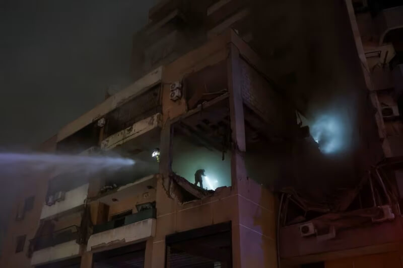 黎巴嫩貝魯特郊區達希耶一棟大樓被炸出大洞，消防人員2日噴水灌救。（路透社）