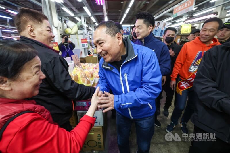 台北市長蔣萬安（後中）4日清晨陪同國民黨總統候選人侯友宜（前中）前往萬華區台北農產公司批發市場拜票，侯友宜與攤商握手問好。中央社記者吳家昇攝 113年1月4日