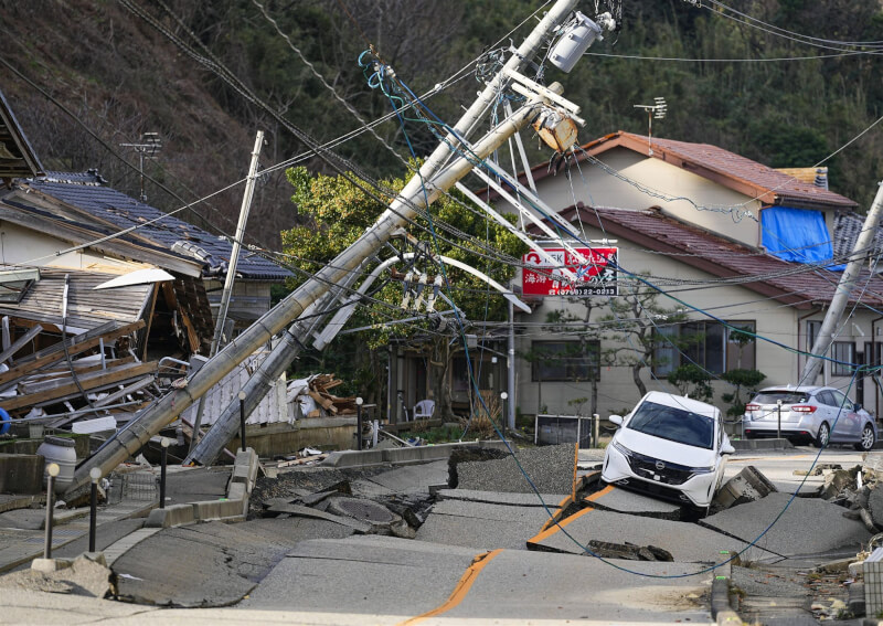 日本地震重創能登半島，輪島市房屋被地震震垮，電線桿倒塌道路隆起。（共同社）