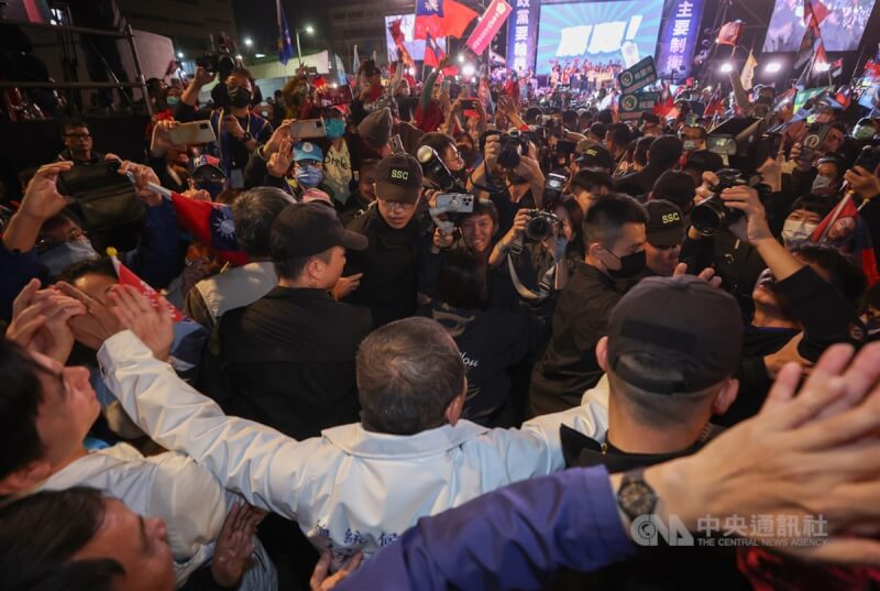 「台灣平安 人民侯康」桃園團結勝利大會6日晚間在中壢區登場，侯友宜（前中白衣背對者）在維安人員包圍下進場，現場群眾熱情相迎，紛紛搶拍、握手、擊掌等，展現侯友宜的高人氣。中央社記者張新偉攝　113年1月6日