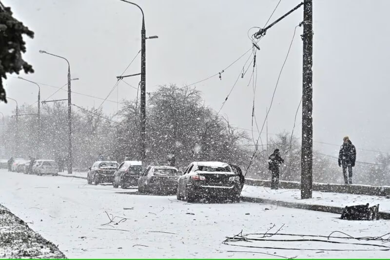 烏克蘭天氣嚴寒，8日扎波羅熱調查人員在雪地中查看受損車輛。（路透社）